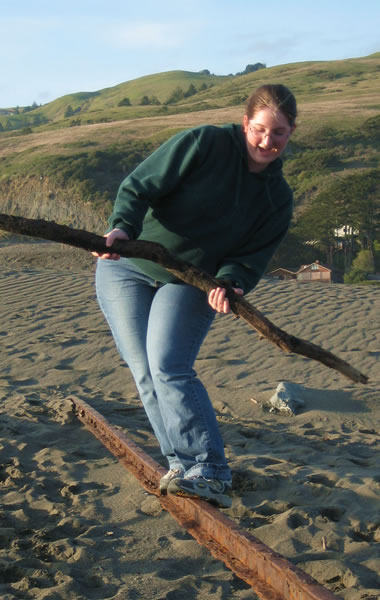 Katie balancing on a railroad track sticking out of a sand dune at Goat Rock Beach