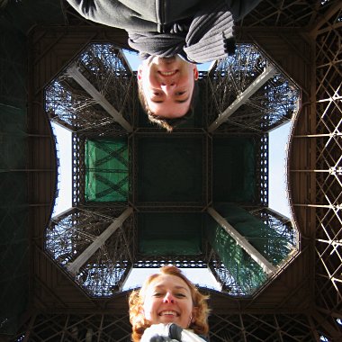 Justin and Stephanie look down at the camera pointing up the Eiffel Tower