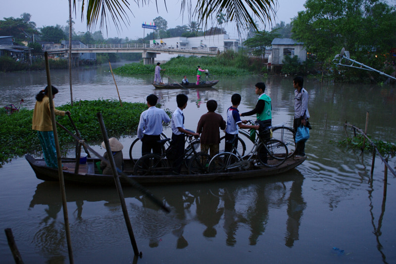 Students with bikes being ferried across the river in the Mekong Delta