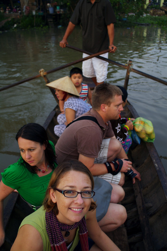 Stephanie squatting on the canoe ferry, crossing a branch of the Mekong Delta
