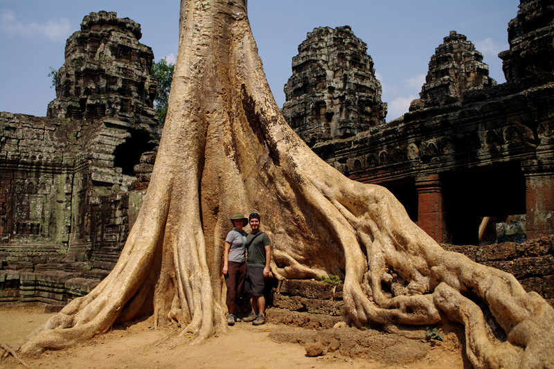 Justin and Stephanie standing at the base of a massive spung tree in Ta Prohm, Angkor, Cambodia