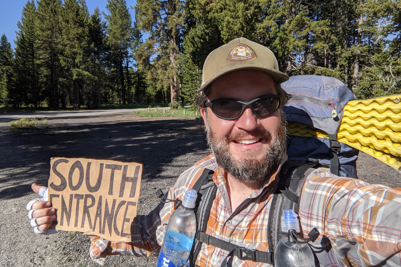 Justin holding a SOUTH ENTRANCE sign in preparation to hitchhike