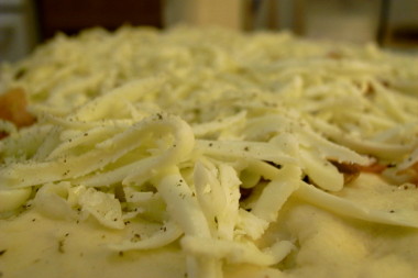 adding the cheese and herbs to the pizza