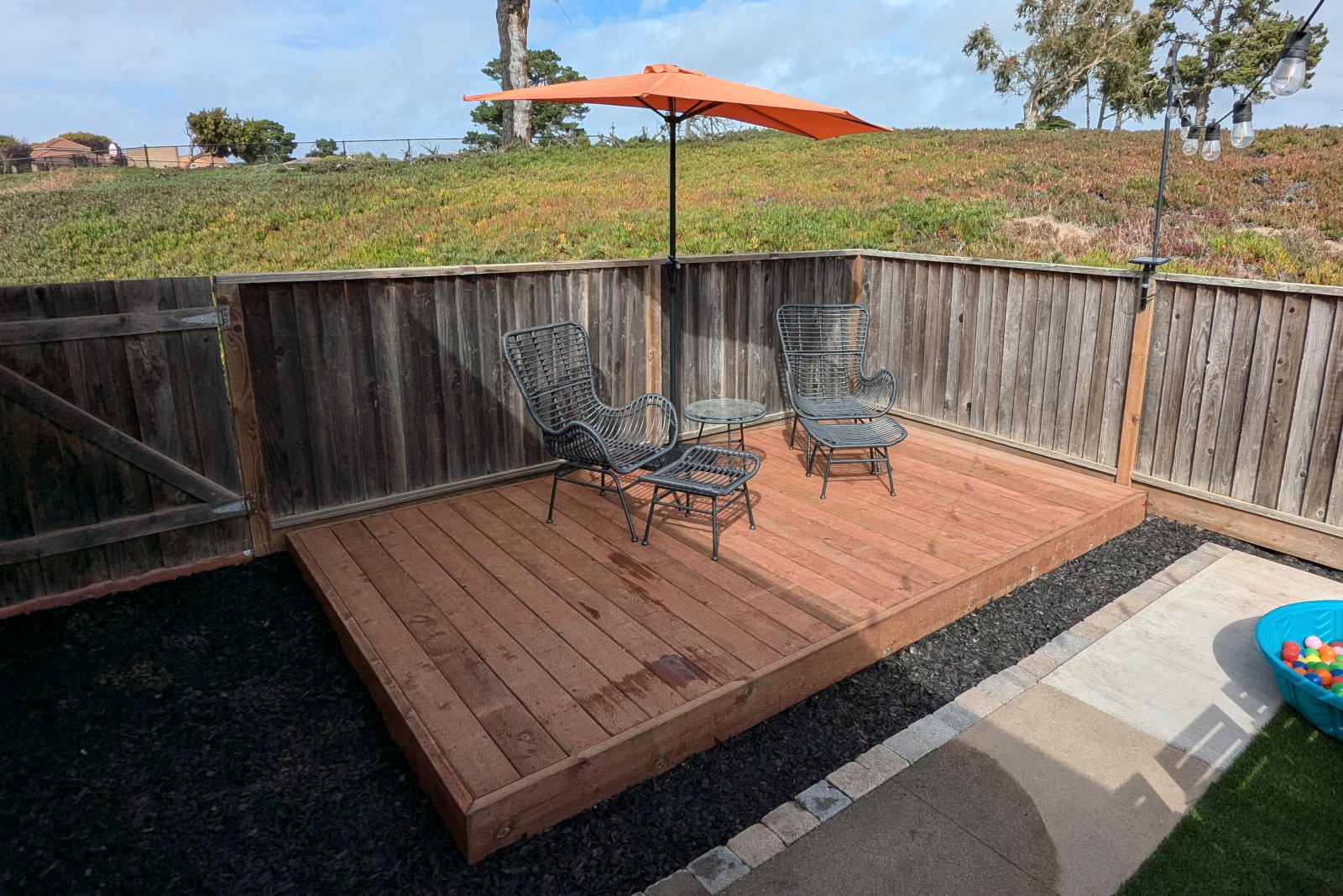 A 13.5x8' floating deck with umbrella, chairs, ottomans, and table