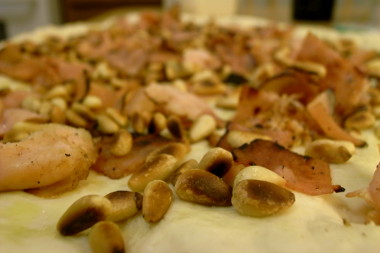 adding the pine nuts to the pizza