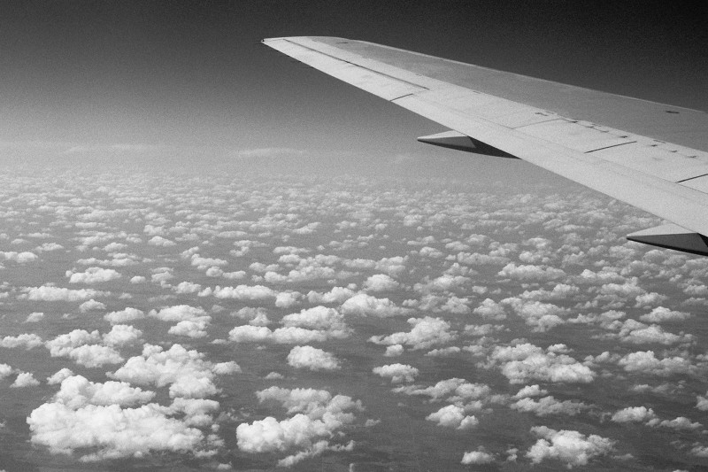 Black and white photo taken in the air above scattered clouds