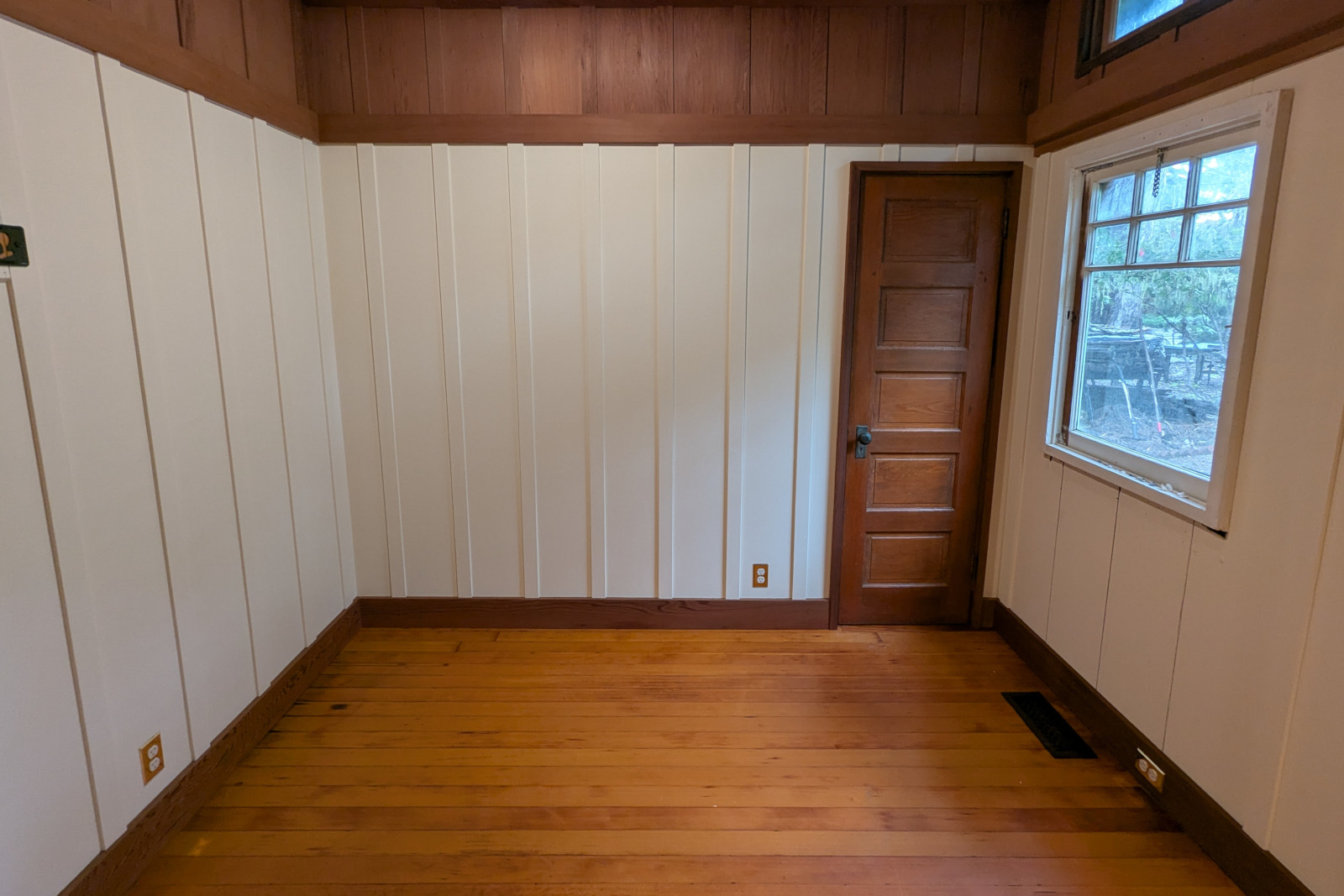 Painted cottage-style bedroom with board and batten walls, against natural redwood baseboards and picture rails