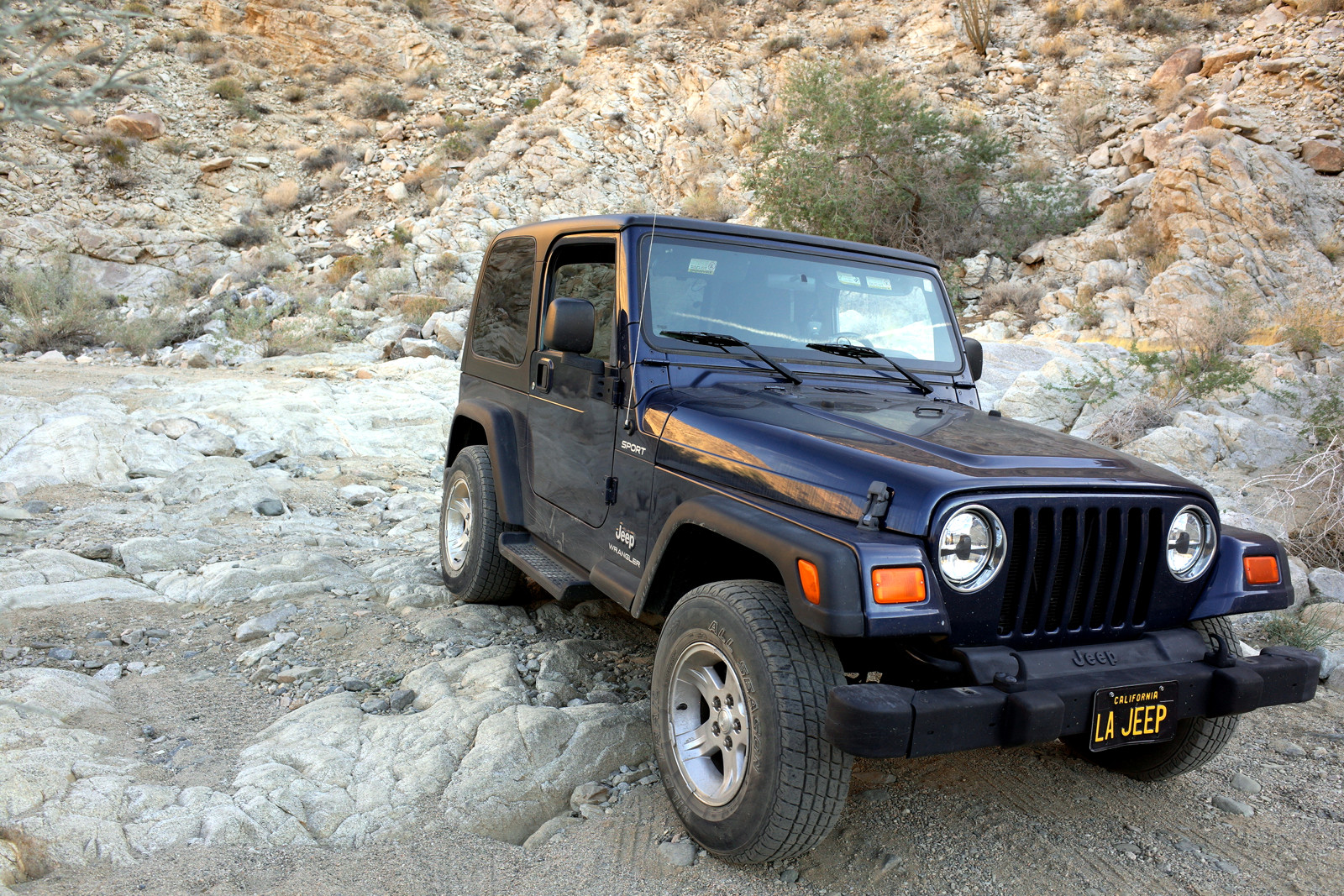 La Jeep straddling the rocky obstacle on Pinkham Canyon in Joshua Tree National Park