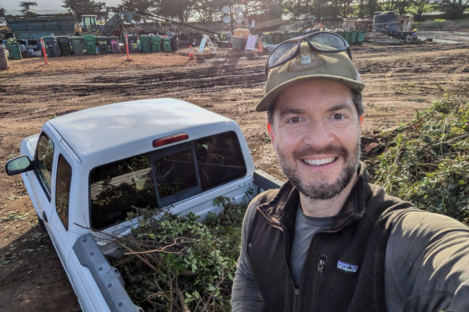 Justin standing on the bed of a white pickup truck bringing a load of compost to the dump