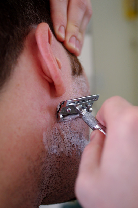 Justin shaving cheek with safety razor