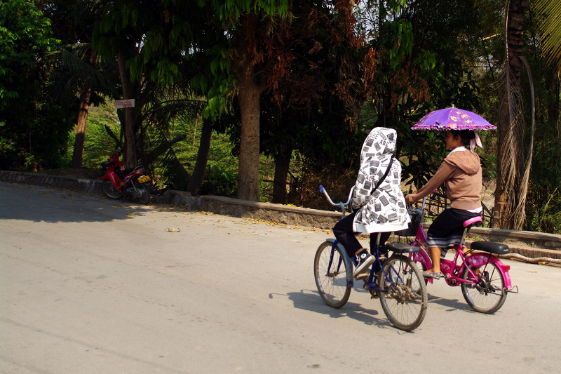 Riding a bicycle with an umbrella in Luang Prabang, Laos