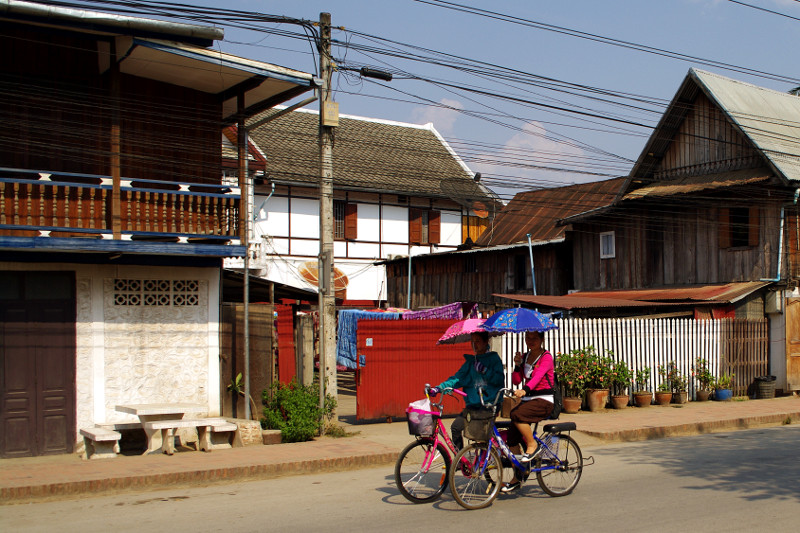 Riding a bicycle with an umbrella in Luang Prabang, Laos