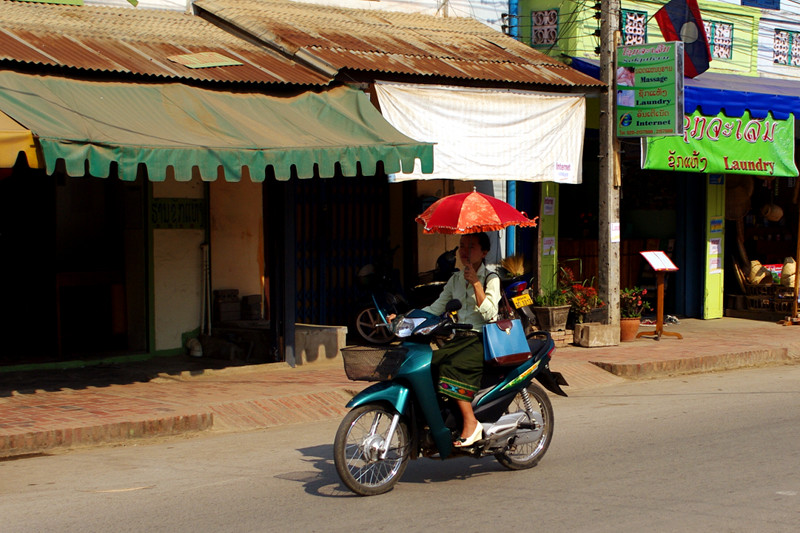 Riding a scooter with an umbrella in Luang Prabang, Laos