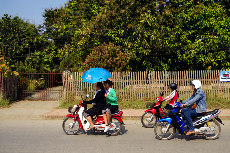 Riding a scooter with an umbrella in Luang Prabang, Laos