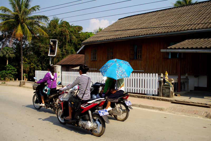 Riding a scooter with an umbrella in Luang Prabang, Laos