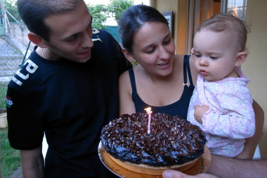 Michel, Aurelie, and Luna blow out the candle on her first birthday cake