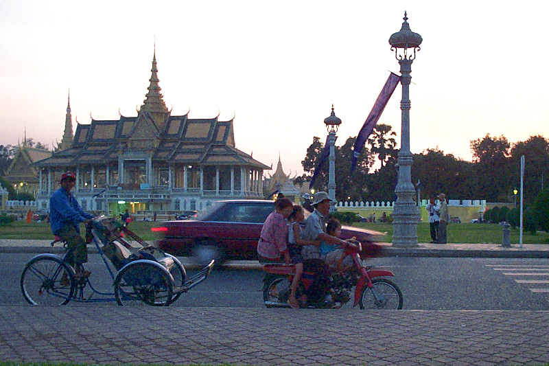 Family of four on a moto in front of the Chan Chhaya Pavilion of the <a href=