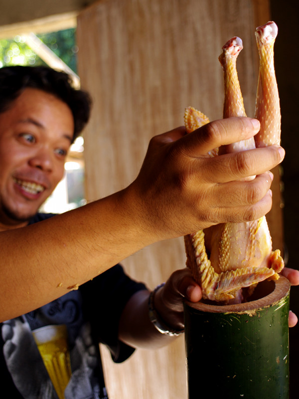 Jeoffrey stuffing a chicken into bamboo for binakol na manok