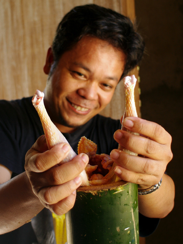 Jeoffrey stuffing a chicken into bamboo for binakol na manok