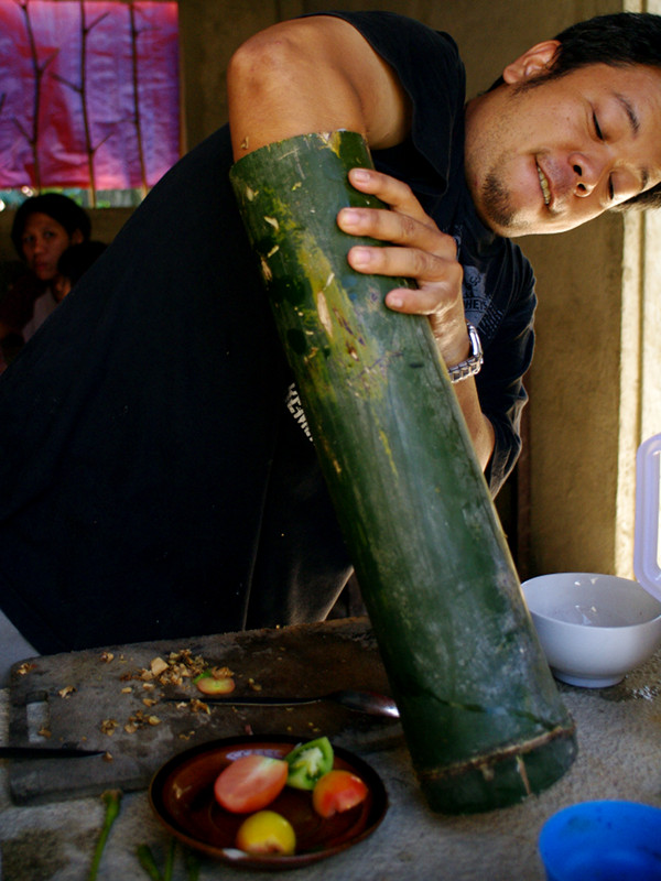 Jeoffrey stuffing a chicken into bamboo for binakol na manok